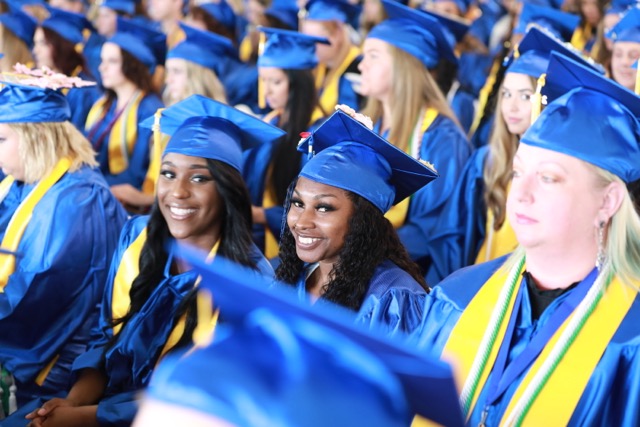 Smiling students in caps and gowns during graduation