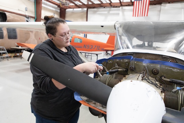 student repairing airplane engine