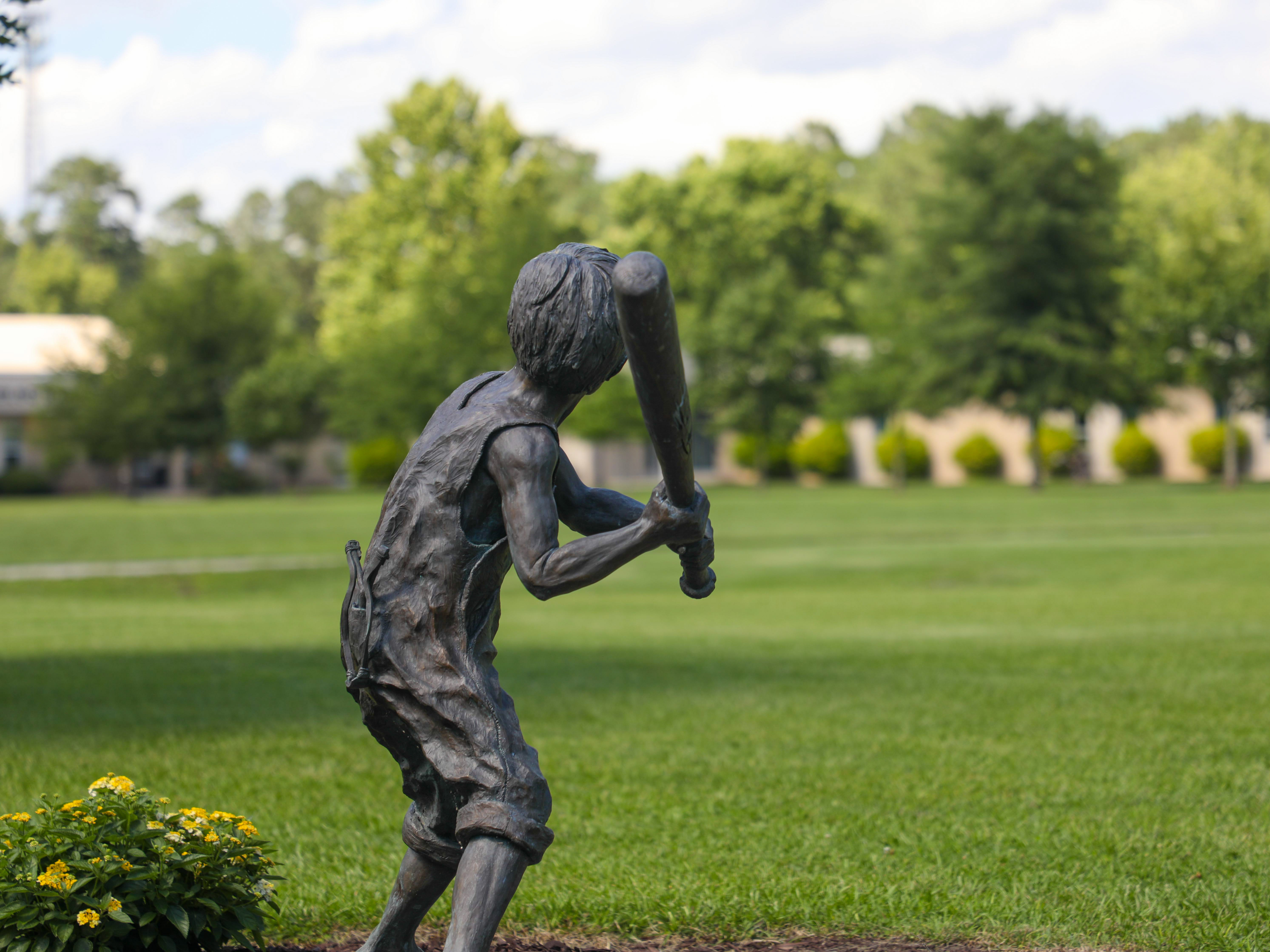 statue of a boy outside who is at bat